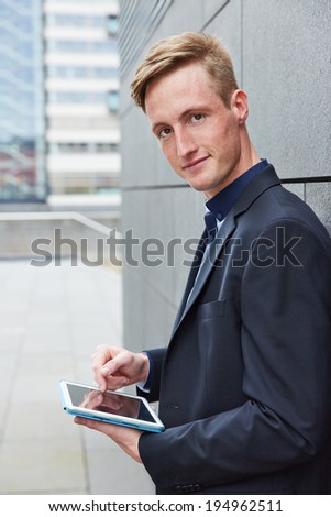 Smiling business man working mobile with tablet computer in the city