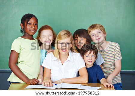 Portrait of happy teacher with group of students in front of chalkboard