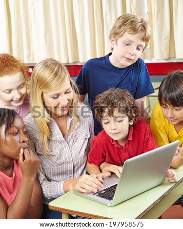 Students and teacher with laptop computer in elementary school class