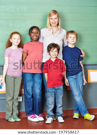 Portrait of teacher and group of elementary school students in front of chalkboard