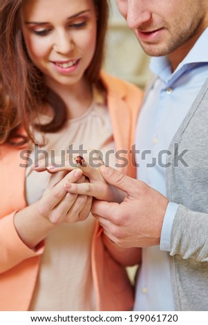 Woman trying ring on finger with her man looking