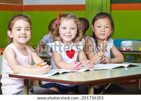 Many happy children drawing in kindergarten with pens and coloring books