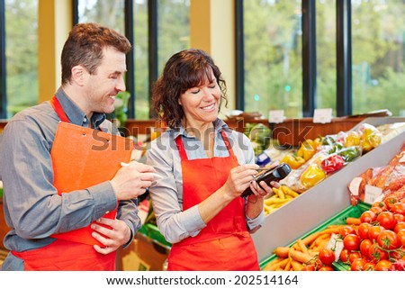Staff in supermarket using mobile data acquisition terminal for vegetables delivery