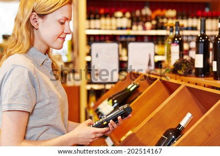Saleswoman counting wine bottles with mobile data registration terminal