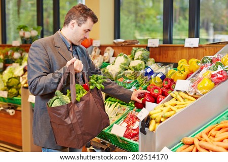 Businessman with shopping bag buying fresh vegetables in a supermarket