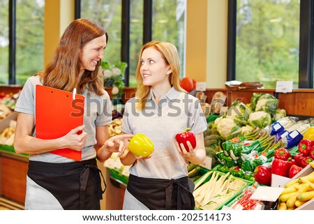 Store manager in supermarket teaching trainee in the vegetables section
