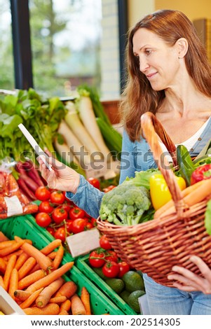 Attractive elderly woman buying vegetables with shopping list in a supermarket