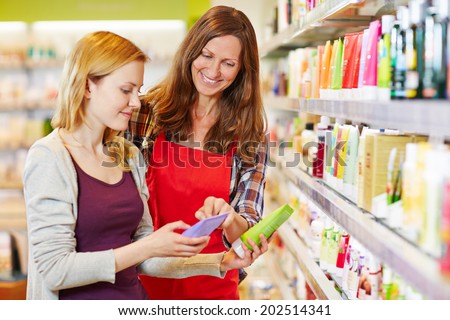 Young woman comparing cosmetics products with saleswoman in a drugstore