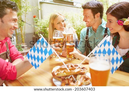 Happy friends in bavarian beer garden drinking beer in summer