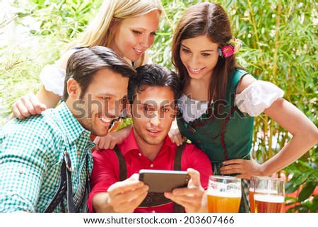 Happy friends taking selfie in bavarian beer garden in summer
