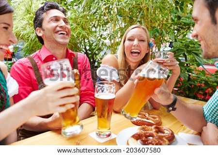 Friends drinking beer and having fun in beer garden in Bavaria