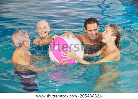 Happy family having fun with water ball in swimming pool in summer