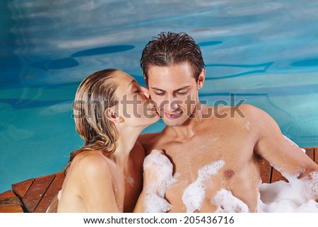 Happy woman kissing man in whirlpool in spa in their holidays