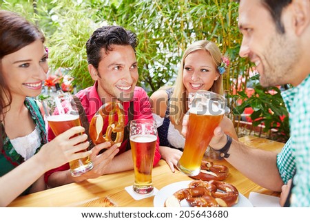 Group of happy friends talking in beer garden in summer in Bavaria