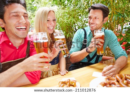 Laughing friends drinking beer together in a garden in summer
