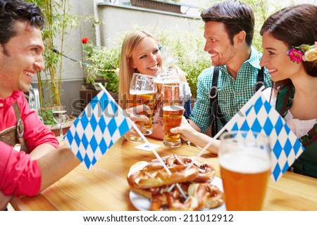 Smiling bavarian friends having fun in beer garden in Germany