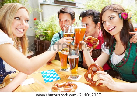 Two happy women clinking beer glasses outside in summer
