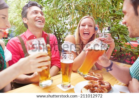 Happy friends laughing in beer garden in summer in Bavaria