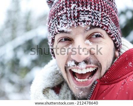 Happy smiling man with snow in his face in winter