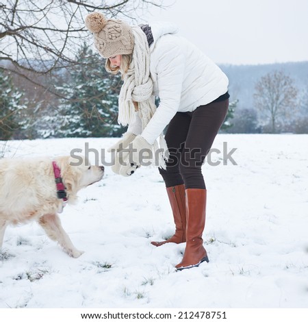 Woman walking a golden retriever dog in snowy winter