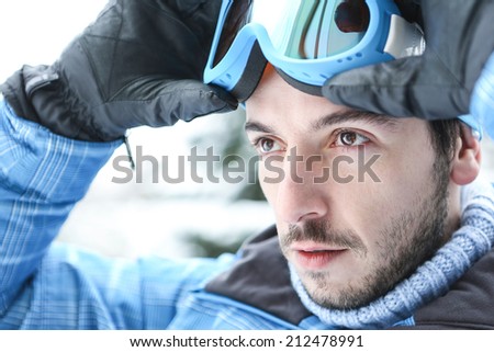 Man in ski holiday putting on his ski googles in winter