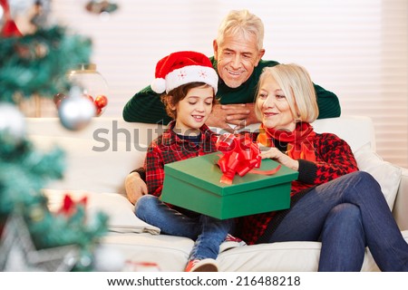 Boy opening gift at christmas with his grandparents