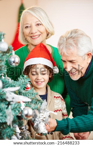 Happy grandparents decorating the christmas tree with their grandson