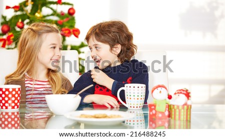 Two happy children eating cookies at christmas at the table