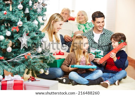 Two children getting gifts at christmas eve from parents and grandparents