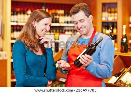Sommelier in wine store giving woman recommendation for bottle of wine