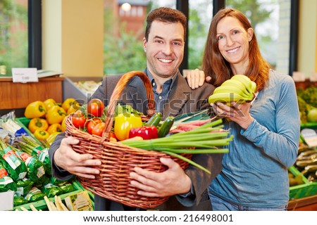 Happy couple buying fresh fruits and vegetables in organic food store