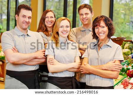 Happy team of smiling men and women staff in a supermarket