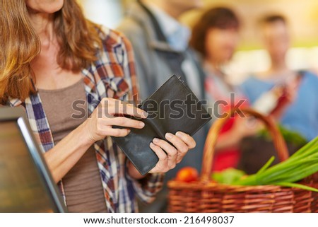 Hand of a woman looking for money in wallet at supermarket checkout