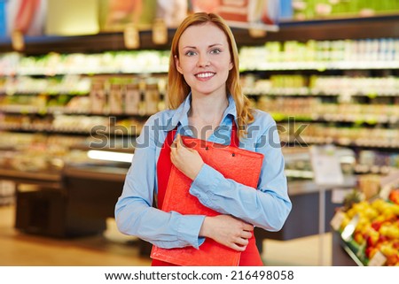 Young female supermarket employee holding a clipboard