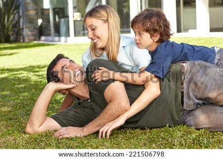 Happy family with son laying in the garden in front of a house