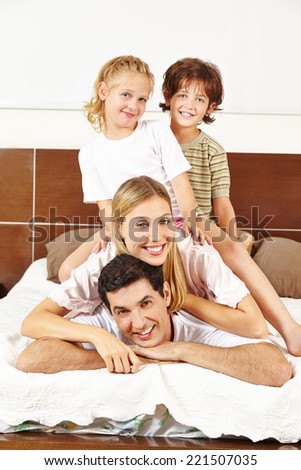 Happy family with two children having fun on bed in the bedroom
