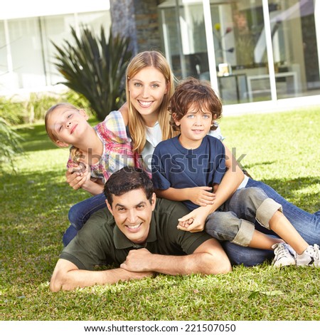 Happy family with daughter and son laying in a garden in front of house