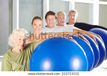 Group of seniors doing fitness training with gym balls in rehab center