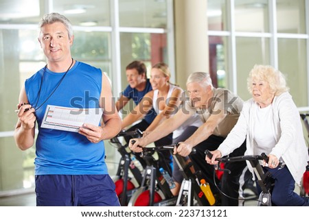 Fitness trainer with senior people on bikes in gym