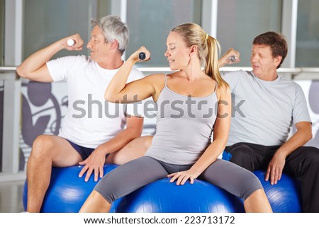 Senior group doing dumbbell training in gym while sitting on exercise balls