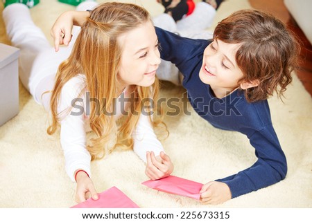 Two happy siblings with greetings cards embracing each other
