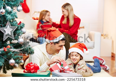 Father and son with gifts at christmas eve with mother and daughter on sofa