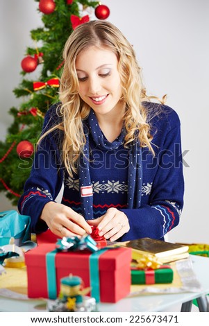 Happy woman wrapping christmas gifts with wrapping paper and ribbon