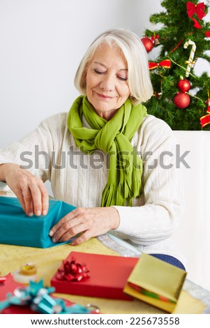 Senior woman wrapping gifts for christmas with wrapping paper