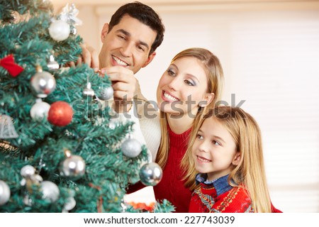 Happy family decorating christmas tree together at home