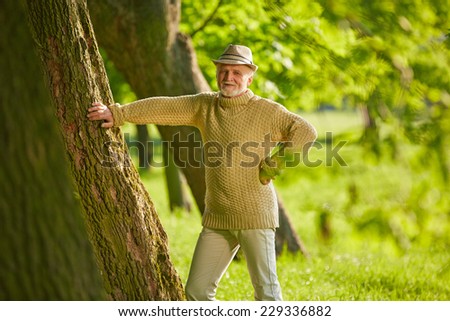 Active senior man leaning on a tree in a forest in summer