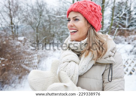 Happy smiling woman standing in winter clothing outdoors in the snow