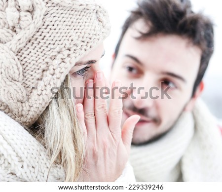 Woman crying near man in winter and wiping tear off her face
