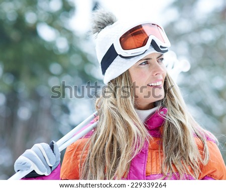 Happy woman in winter with ski goggles on a ski trip holding poles