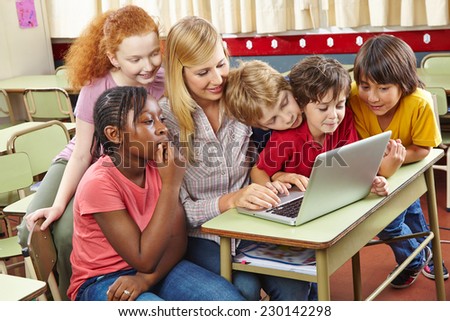 Children at laptop computer in elementary school with teacher